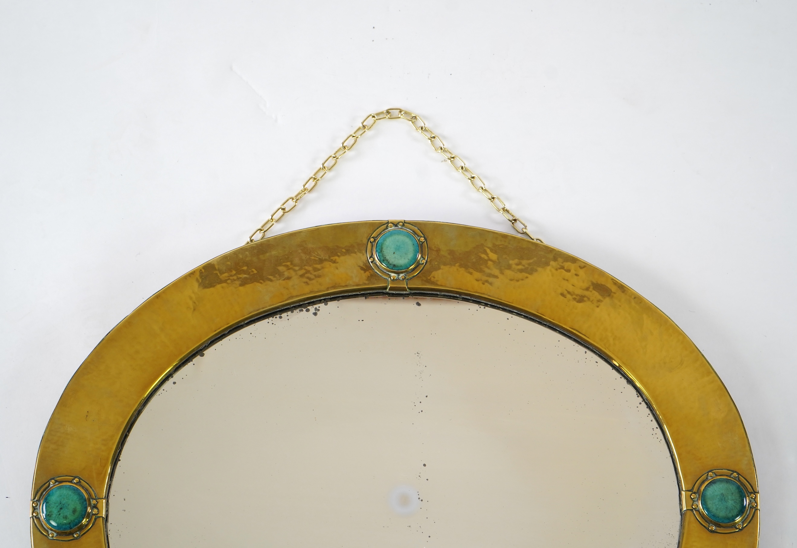 Liberty & Co.: An Arts And Crafts brass and Ruskin pottery cabochon mounted mirror